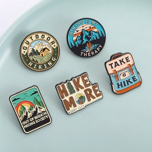 Five outdoor hiking enamel pins with mountain scenery and motivational quotes on a tray