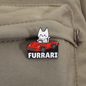 Detailed close-up of a white cat enamel pin driving a red Furrari sports car on fabric