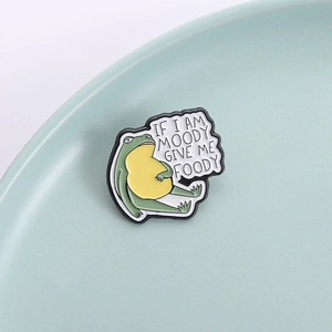 Spilla in smalto a forma di rana divertente con scritta Moody Foody su sfondo verde menta