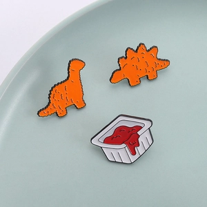 Cute dinosaur chicken nugget and tomato sauce enamel pin set in a ceramic dish