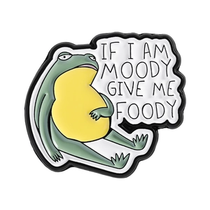 Funny green frog enamel pin with 'If I am moody give me foody' text design on white background