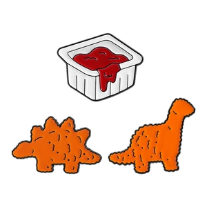 Cute enamel pin set featuring dinosaur chicken nuggets and tomato sauce dip container