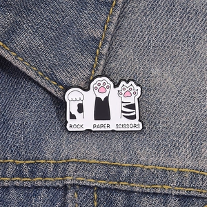 Cute black and white cat paw enamel pins featuring rock paper scissors on denim jacket