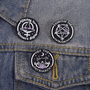 Lot de trois broches en émail noir féministe sur une veste en jean bleue