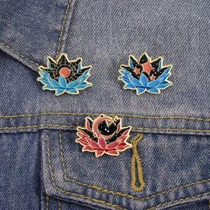Three lotus flower enamel brooches with sun and moon elements on denim jacket