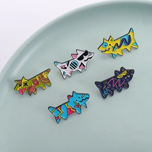 Set of five colorful geometric dog enamel pins with artistic graffiti patterns on a ceramic plate