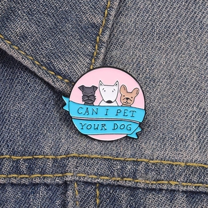 Detalle del pin esmaltado redondo con perros y texto sobre chaqueta vaquera
