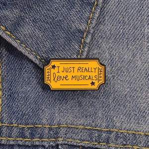 Pin's en émail ticket comédie musicale avec slogan I Love Musicals sur jean