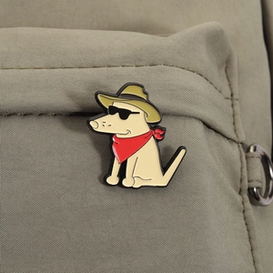 Detail of a cartoon dog enamel pin with cowboy hat on a green canvas backpack