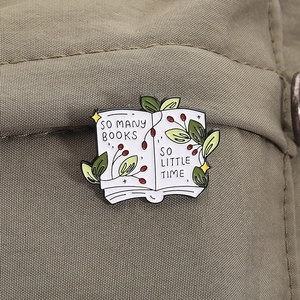 Close-up of enamel book brooch with green leaves on olive green canvas fabric