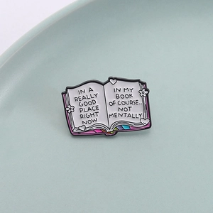 Enamel book brooch with humorous quote and floral design on a minimalist background