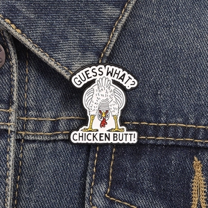 Dettaglio di una spilla smaltata ironica con pollo su una giacca di jeans blu
