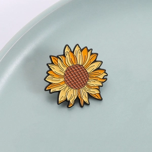 Vibrant sunflower enamel brooch pin with yellow gradient petals on a grey background