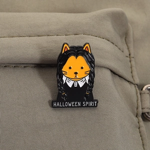 Détail d'un pin's en émail chat orange sur un sac à dos avec texte Halloween Spirit