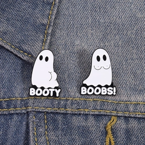Detail of funny ghost enamel pins with text on blue denim fabric texture background