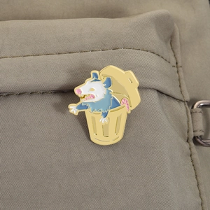 Primer plano de un pin esmaltado de zarigüeya en basurero sobre mochila de tela caqui