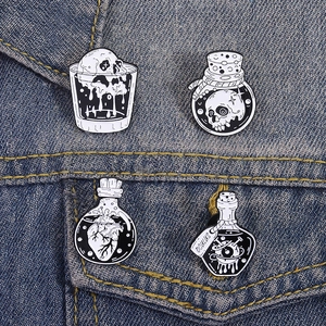 Macro detail of four Gothic enamel pins featuring skull and heart designs on denim jacket