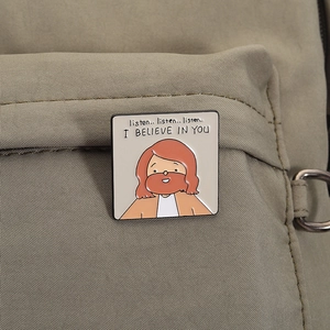 Close-up of square enamel pin with motivational text on a canvas backpack detail