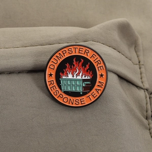 Détail du pin's émaillé Dumpster Fire Response Team sur un tissu beige doux