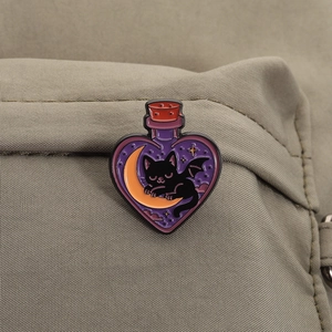 Macro shot of a heart-shaped magic bottle enamel pin with a bat cat on a crescent moon