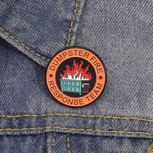 Dettaglio macro della spilla smaltata Dumpster Fire Response Team su jeans blu