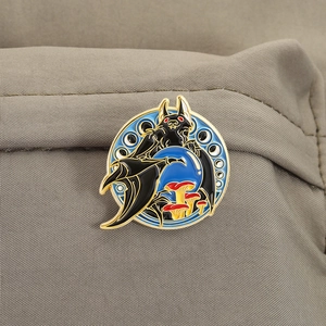 Detail of round enamel bat brooch with mushrooms and blue moon on grey fabric