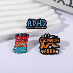 Three enamel ADHD and Autism awareness pins with battery and ribbon designs on white stands