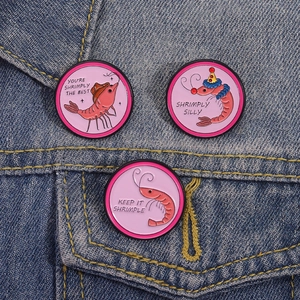 Trois pin's émaillés crevettes sur veste en jean bleue avec jeux de mots roses amusants