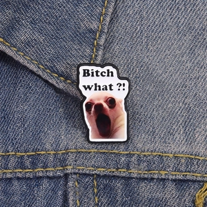 Detail of funny Chihuahua meme enamel pin on denim jacket collar featuring Bitch What text