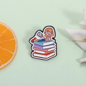 Épingle en émail de dessin animé montrant une fille avec casque lisant sur des livres