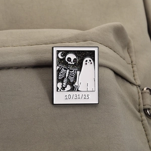 Macro shot of a Polaroid style Halloween ghost and skeleton pin on a khaki fabric bag