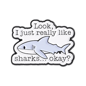Cute cartoon shark enamel pin with 'I just really like sharks' text in light blue