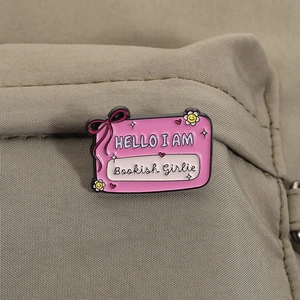 Détail d'un badge émaillé Bookish Girlie avec nœud et fleur sur tissu canevas
