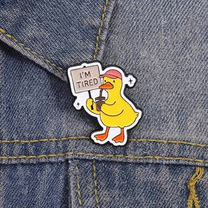 Nahaufnahme einer müden gelben Enten-Emaille-Anstecknadel mit I'M TIRED Schild auf Denim