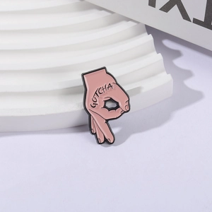 Broche en émail rose en forme de geste de la main OK avec texte noir Gotcha stylisé