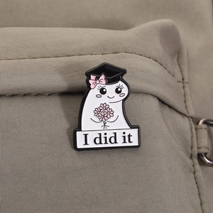 Detailed close-up of a graduation ghost enamel pin with academic cap on a khaki backpack