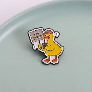 Emaille-Anstecknadel mit müder gelber Ente und I'M TIRED Schild auf einem Keramikteller