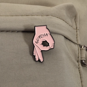 Gros plan détaillé d'un pin's en émail rose avec texte GOTCHA sur un sac en toile