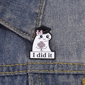 Detail view of a cute cartoon ghost graduation brooch on a blue denim jacket with 'I did it' text