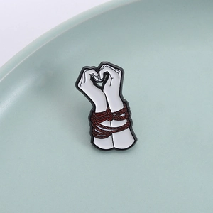 Artistic hand heart enamel pin with red rope detail for dark sweet aesthetic style