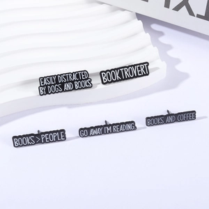 Five-piece black enamel booktrovert pin set with white reading quotes on a stand
