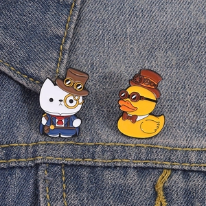 Steampunk enamel pins featuring a cat in a tuxedo and a duck with gear hat on denim