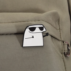 Detail view of the Flork enamel pin with sunglasses pinned on a green canvas backpack