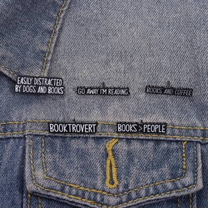 Funny bookworm enamel pin set with reading slogans on classic blue denim jacket