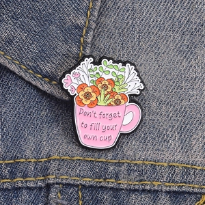 Pink enamel cup pin with flowers on denim, featuring Don't forget to fill your own cup text