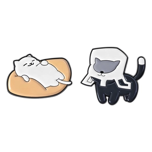 Pair of cute enamel pins featuring a sleeping white cat and a black cat with a paper bag