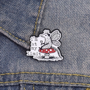 Funny skunk fairy on mushroom enamel pin with i'm at my limit text on denim fabric