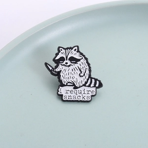 Funny raccoon enamel pin holding a knife with 'i require snacks' text on a ceramic tray
