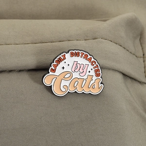 Detail of EASILY DISTRACTED by Cats enamel pin on olive green textured fabric