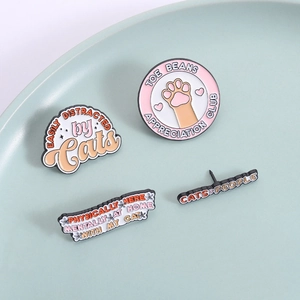 Set of 4 cute cat themed enamel pins with paw prints and cat lover quotes on ceramic tray
